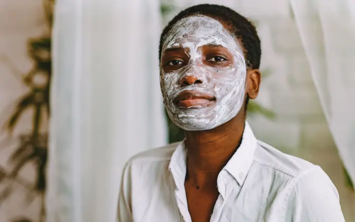 Skincare routine for black skin: portrait of a woman with a facial mask in a calm indoor setting, emphasizing skincare