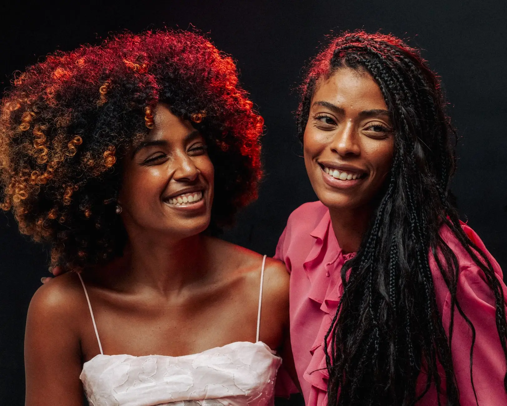 Two friends smiling warmly in vibrant attire, embodying joy and friendship