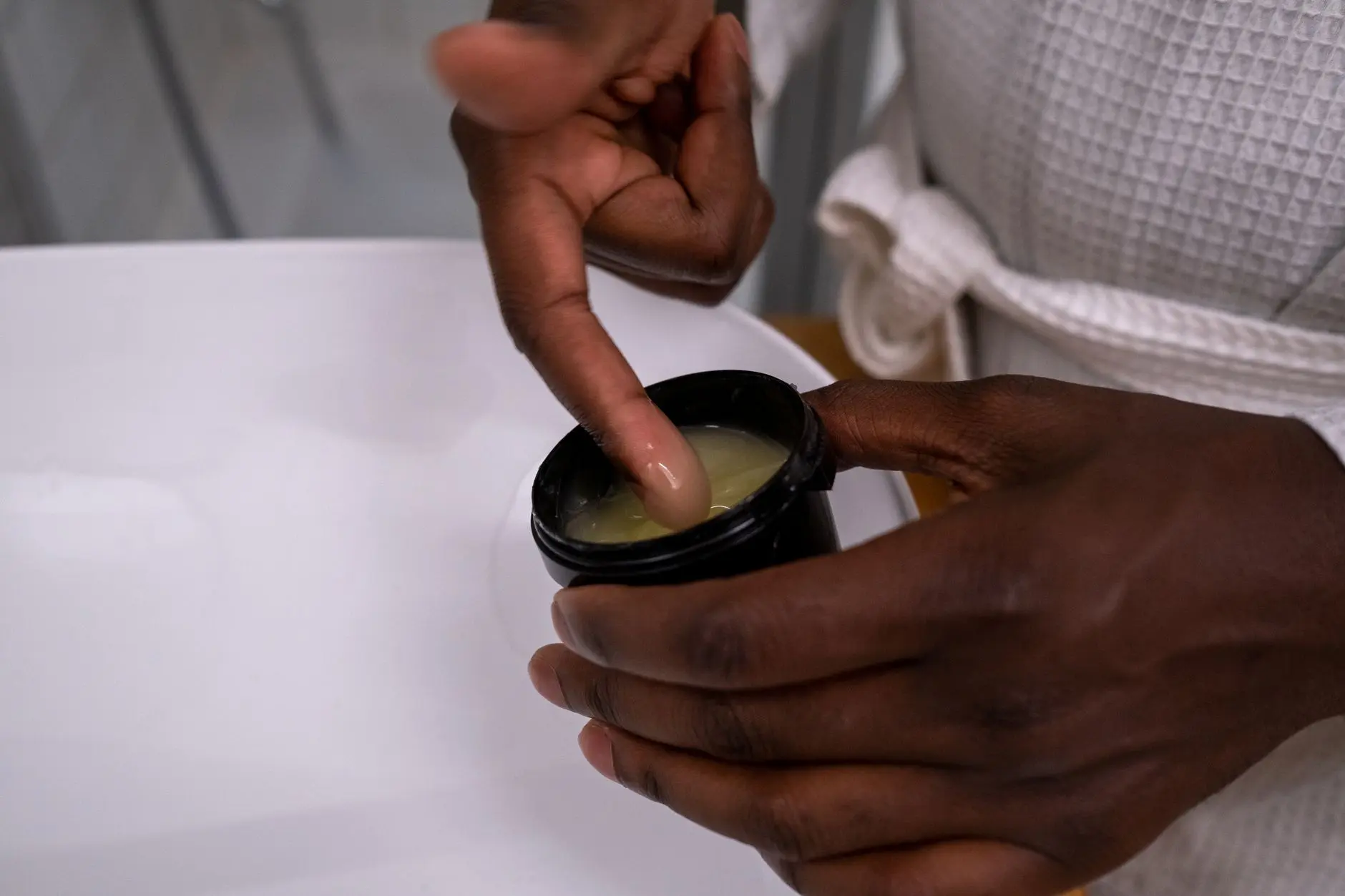 Detail of hands applying moisturizing cream from a container. Ideal for skincare and beauty concepts