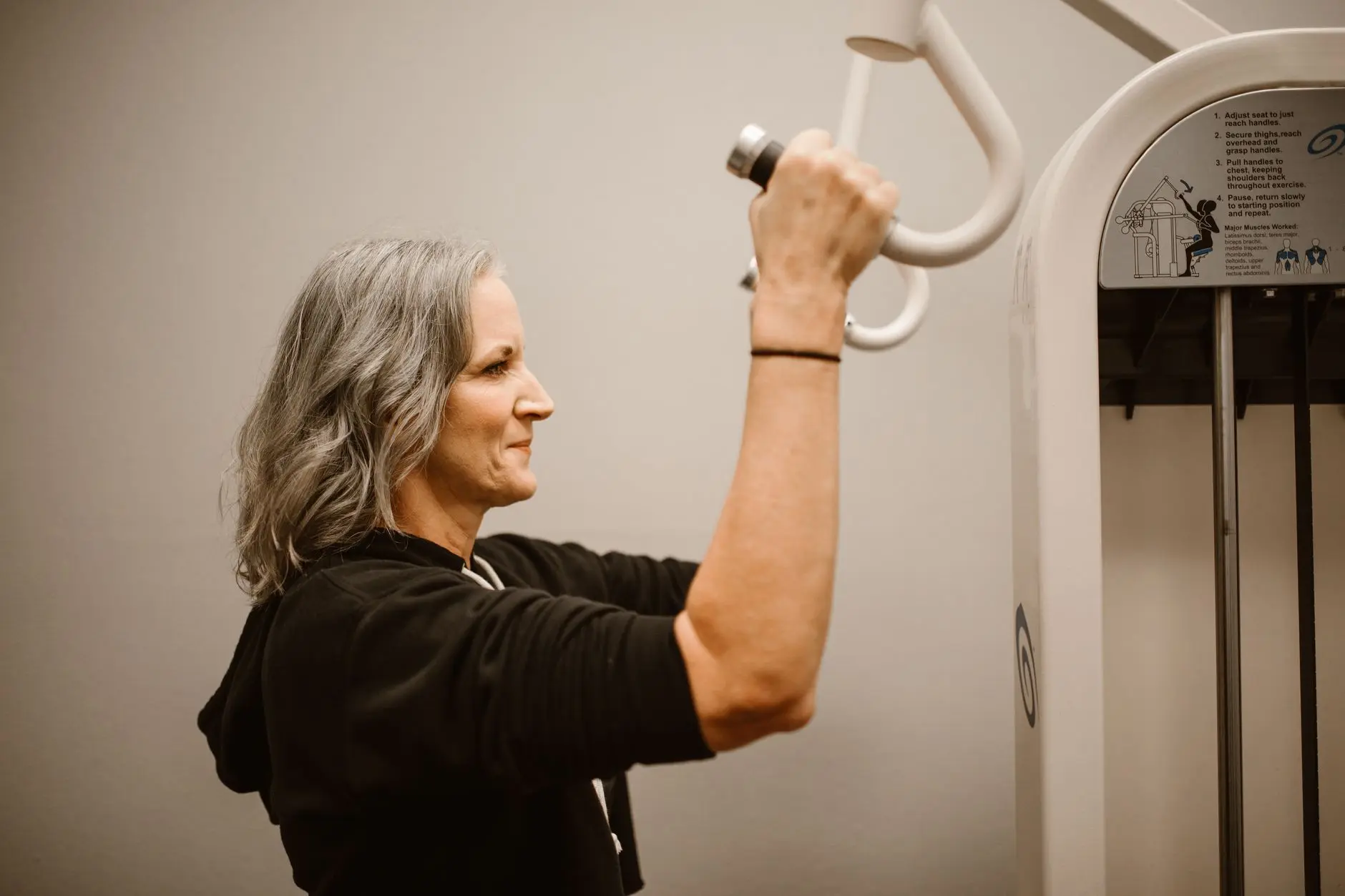 Active senior woman working out on gym equipment, focusing on strength and wellness