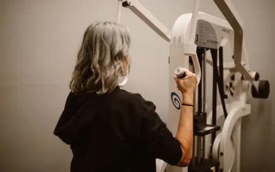 Senior woman uses the lat pulldown machine in a gym for strength training.