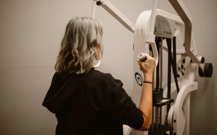 Senior woman uses the lat pulldown machine in a gym for strength training.