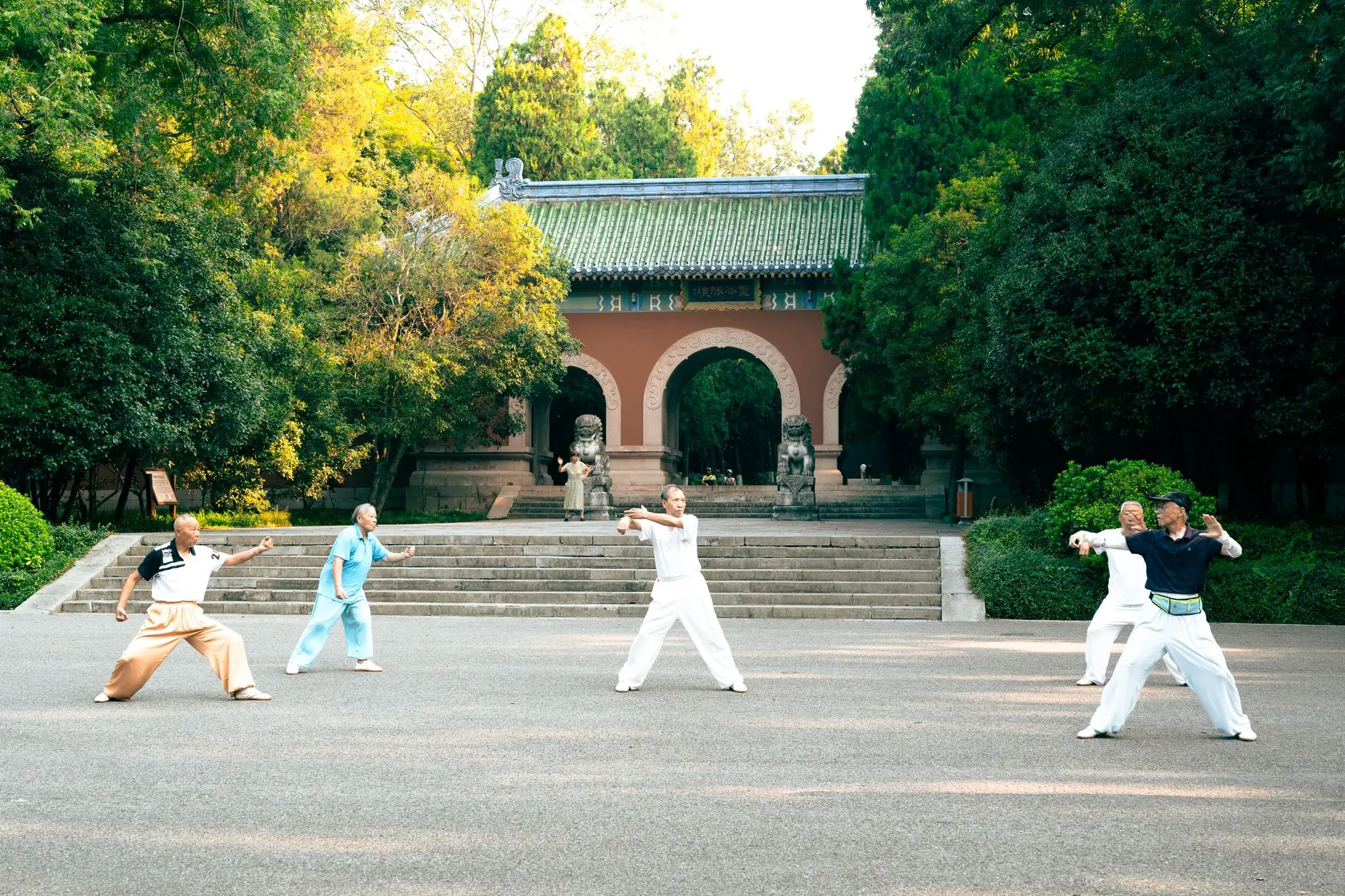 A group practicing Tai Chi near Linggu Temple in Nanjing, China, surrounded by lush green trees