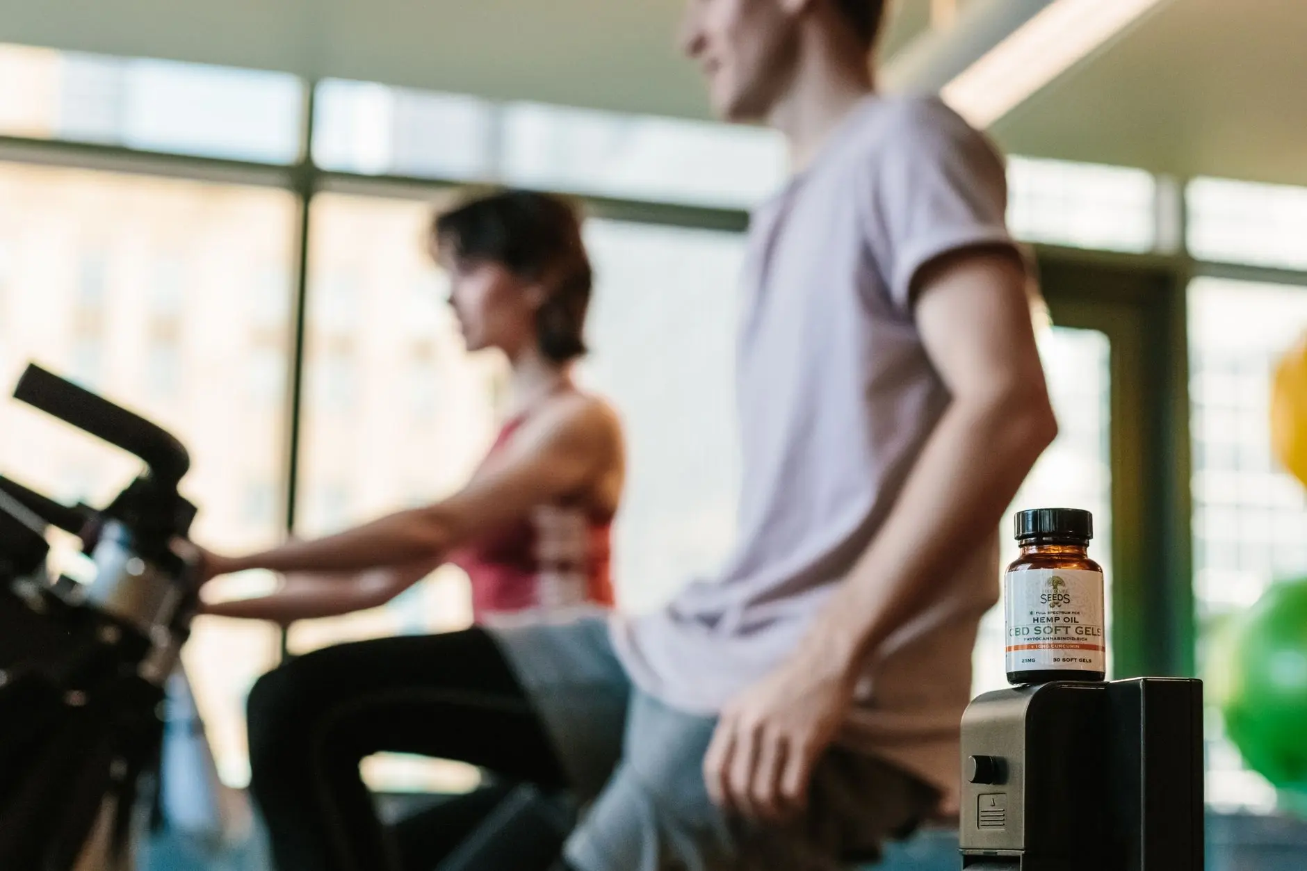 CBD gel bottle in gym with exercising adults, suggesting health benefits