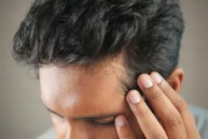 Can vitamin d deficiency cause hair thinning: close-up of a man's hand touching his head in contemplation