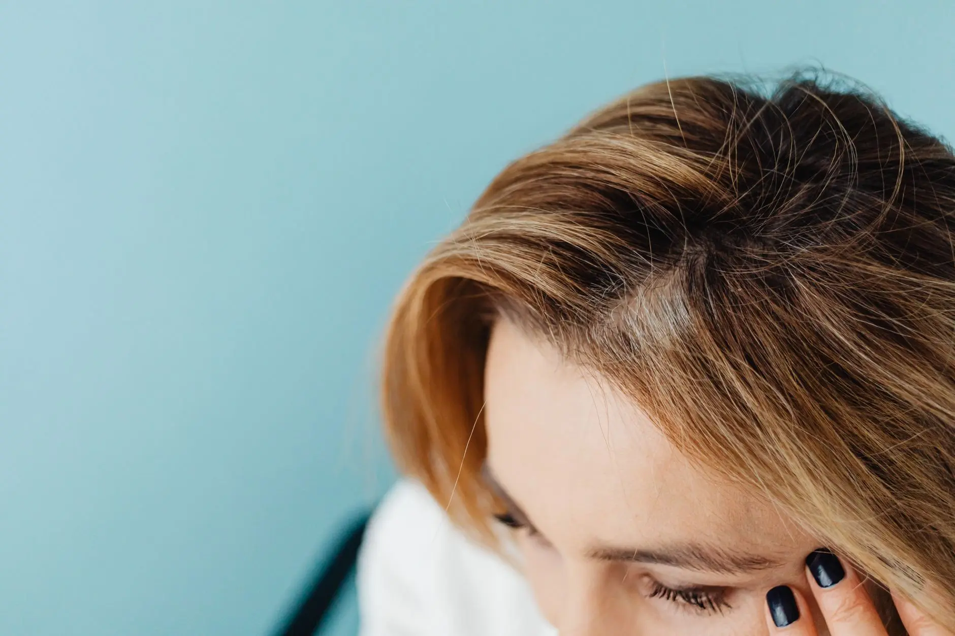 Close-up of a woman with a hand on forehead against a blue background