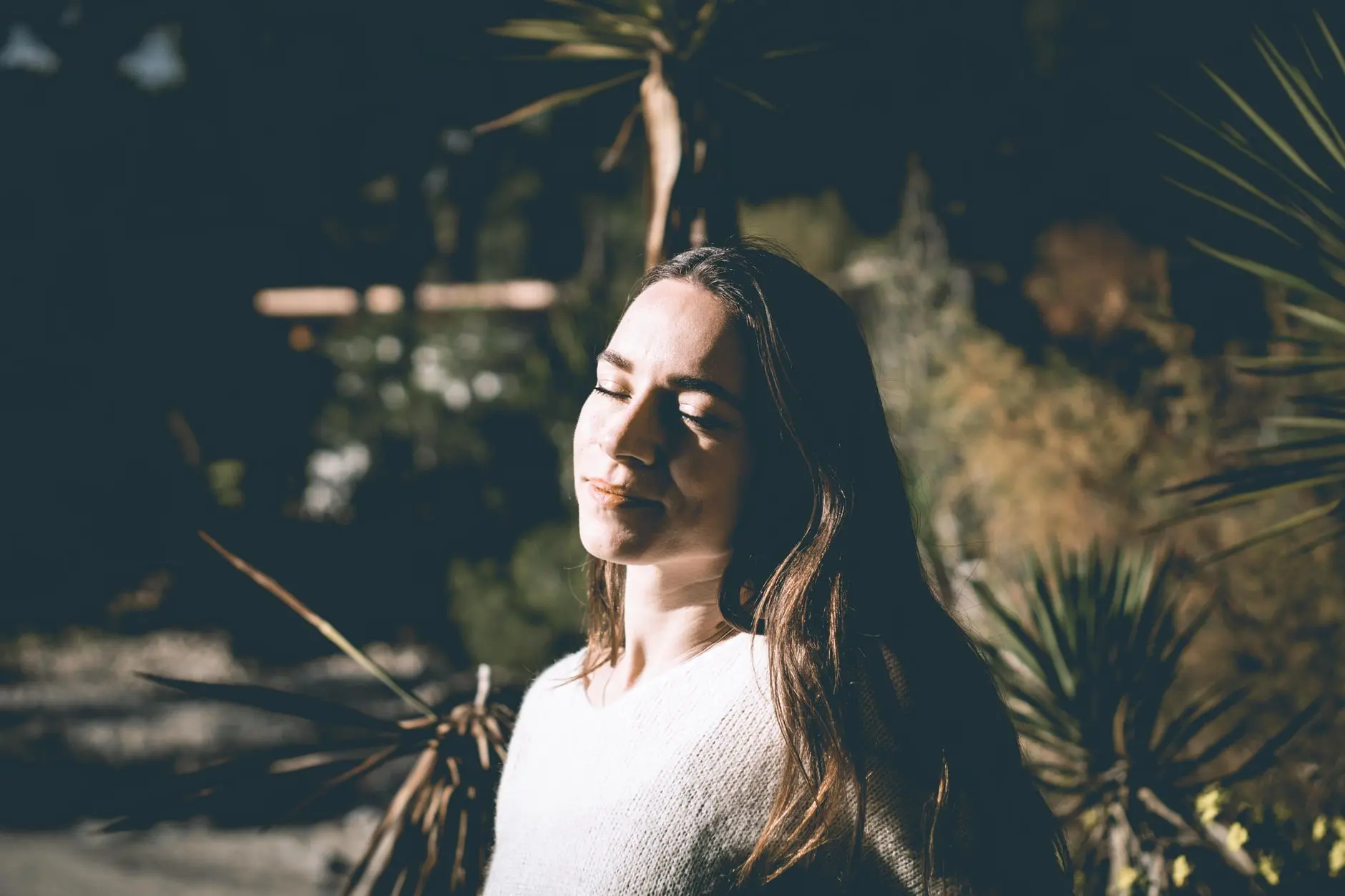Woman enjoying serene outdoor moment with eyes closed in sunlight, Felanitx, Spain