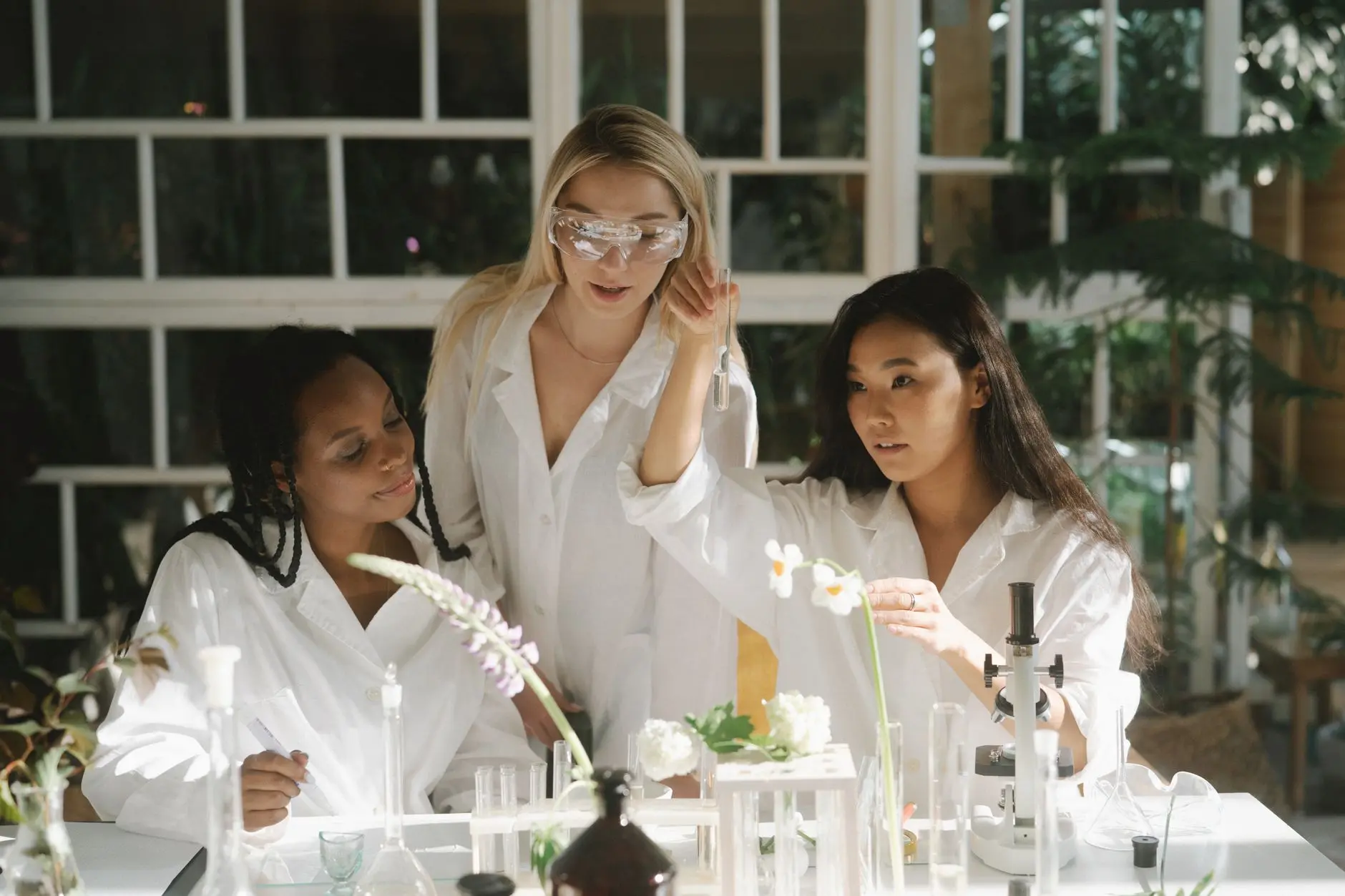Three women scientists in a lab examining plants and using various laboratory equipment