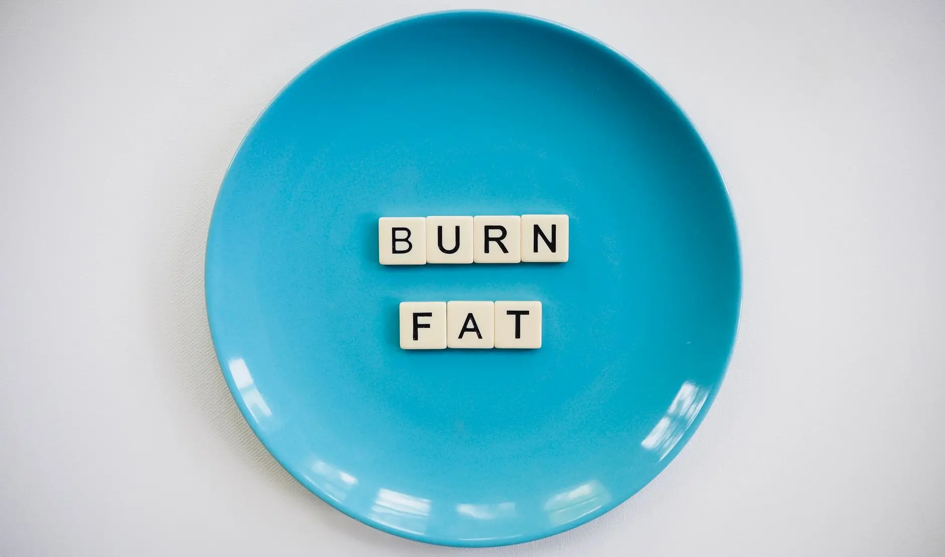 A conceptual image featuring the words 'Burn Fat' on a blue plate, symbolizing weight loss