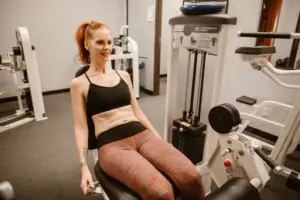 Hormone imbalance signs in women: woman performing leg workout in gym, showcasing fitness and health lifestyle