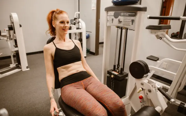 Hormone imbalance signs in women: woman performing leg workout in gym, showcasing fitness and health lifestyle