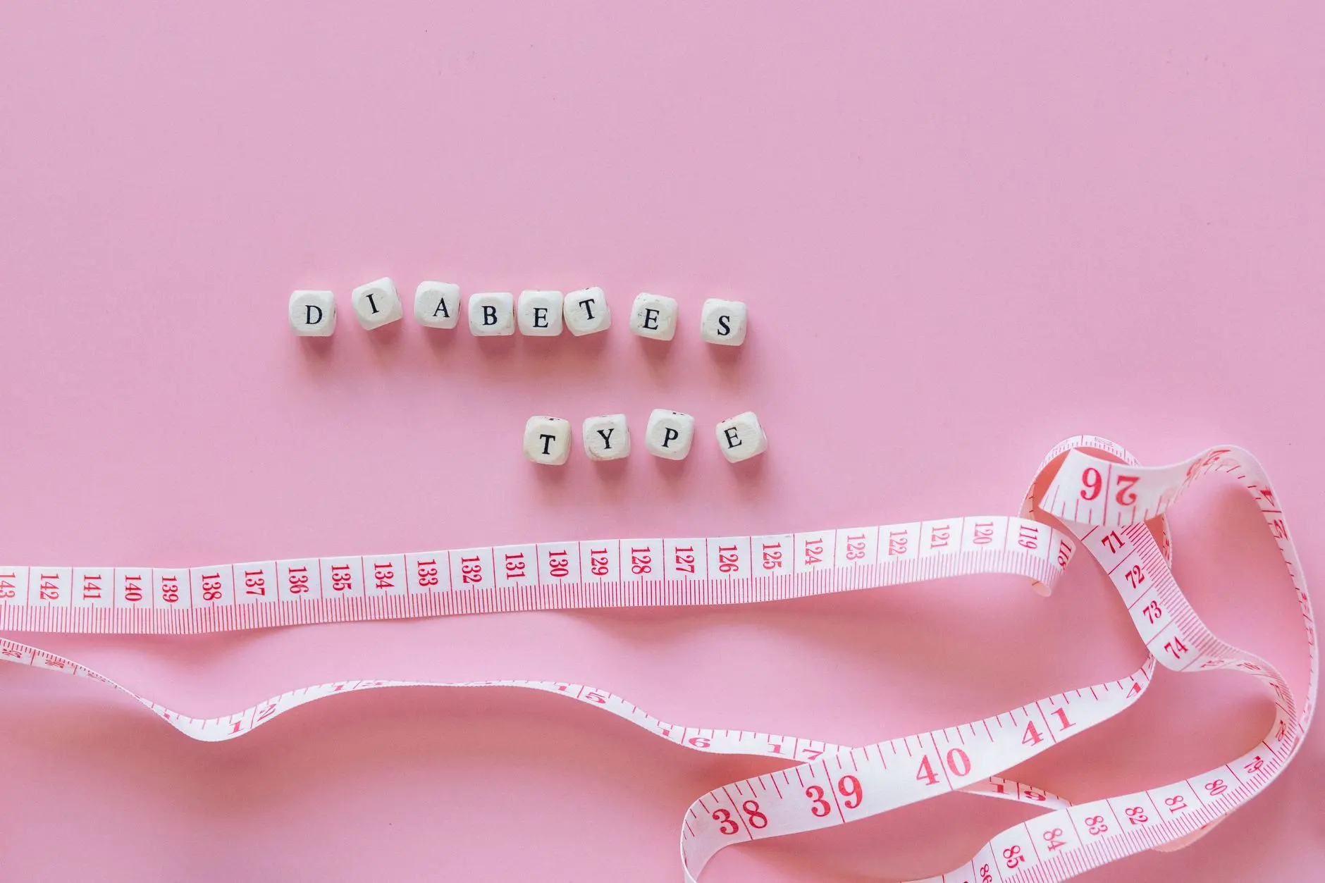 Close-up of diabetes type block letters and measuring tape on pink background
