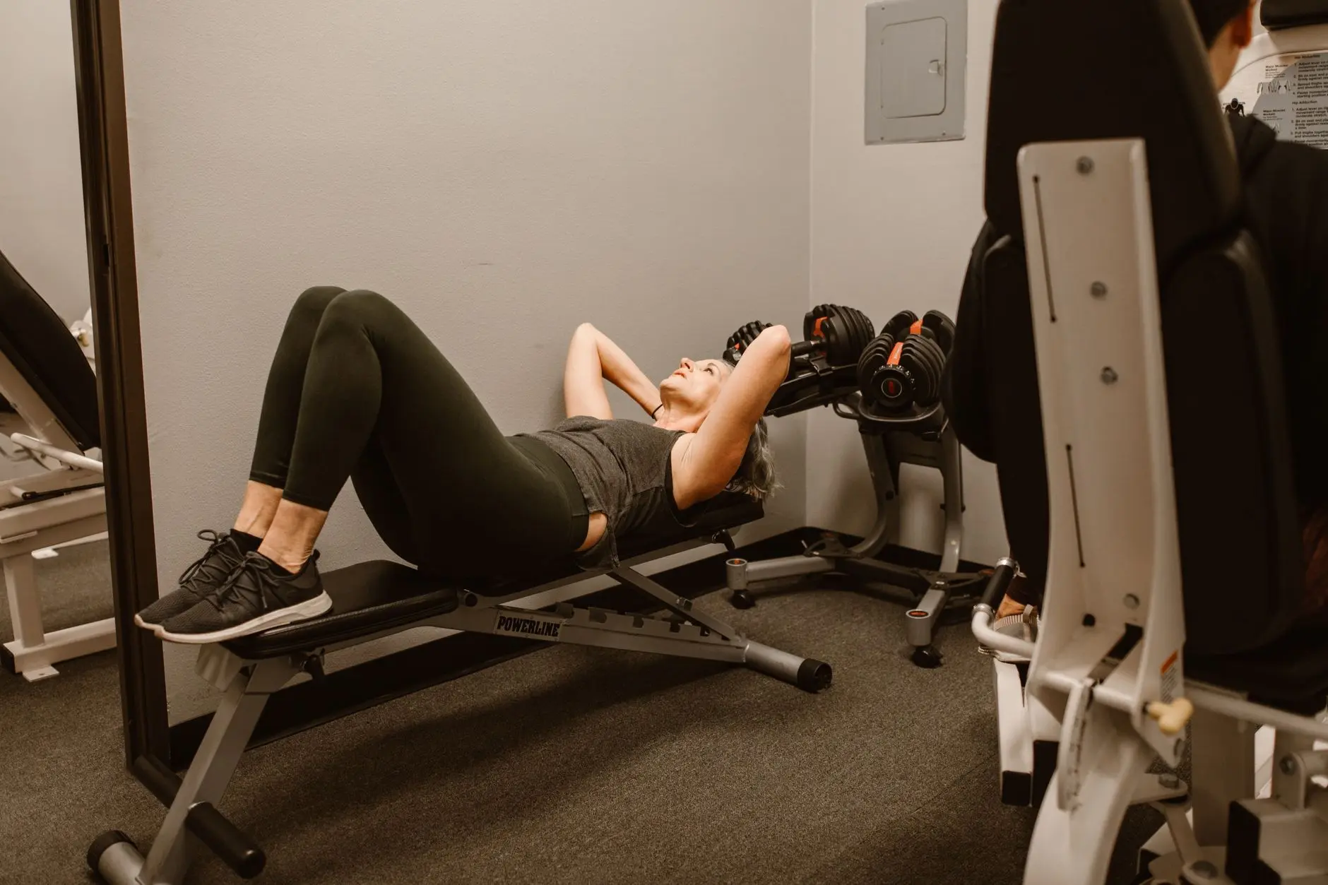 Adult woman exercising on a bench in a gym, promoting fitness and healthy lifestyle