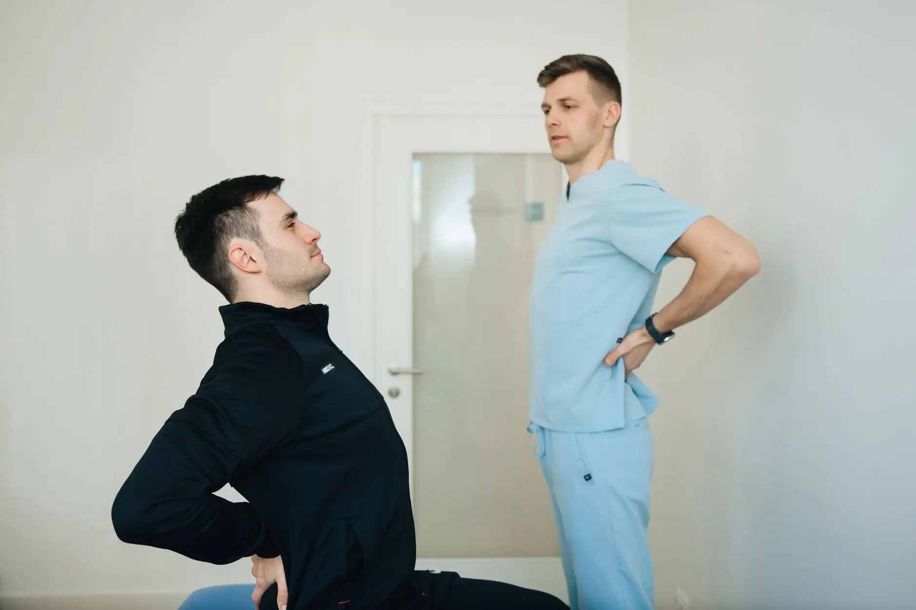 A physiotherapist instructs a patient on back exercises in a clinic setting