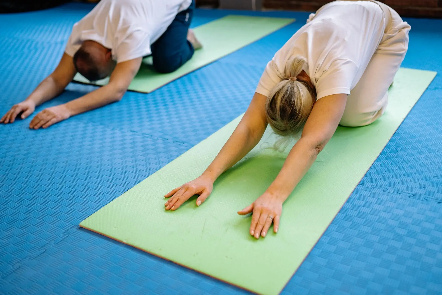 Senior adults stretching on yoga mats inside a gym, promoting health and fitness