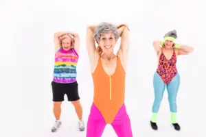 Strength training exercises for women over 60: senior women in vibrant activewear enjoying an aerobic exercise session with