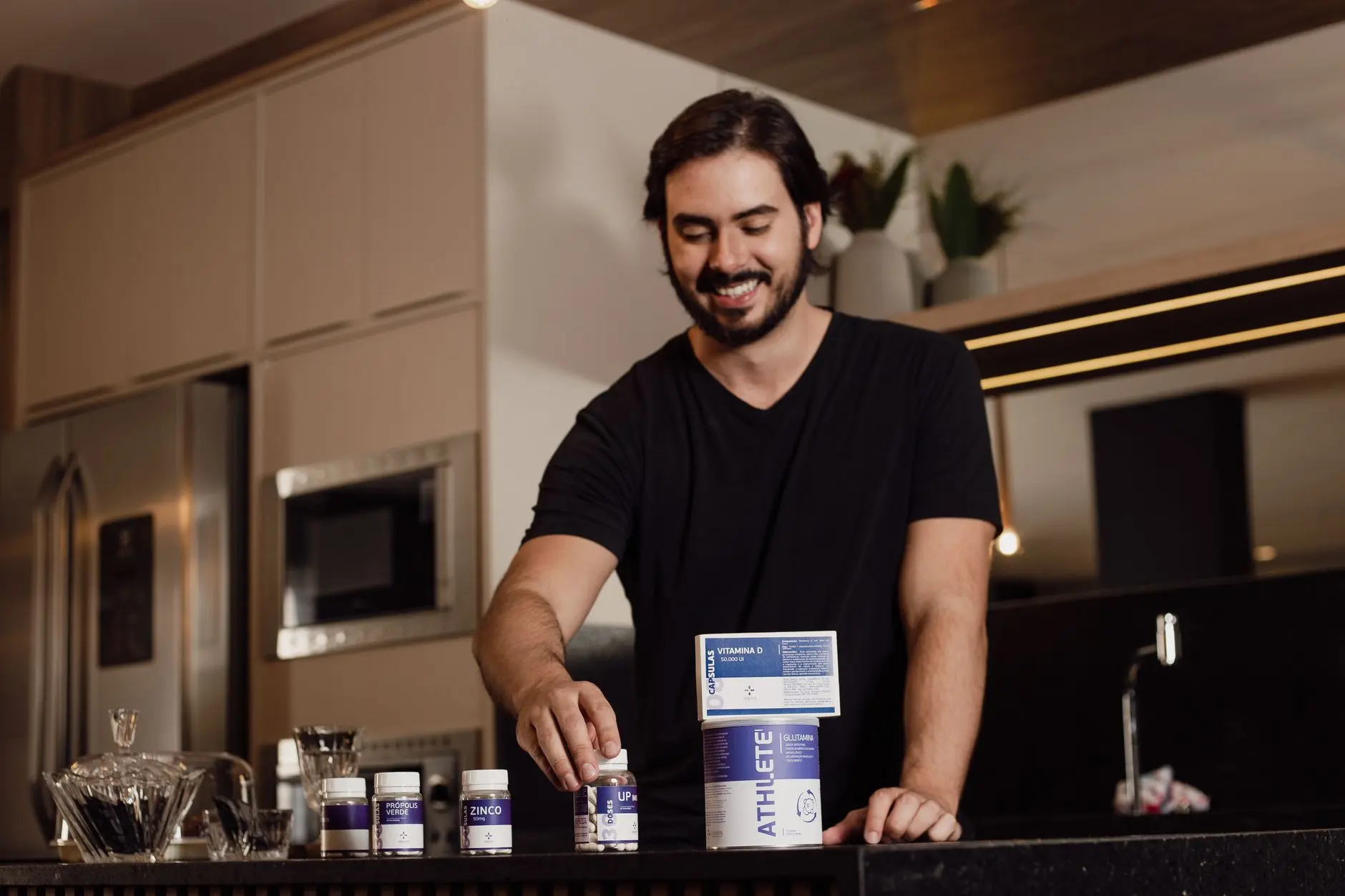 Smiling man arranging vitamin supplements on kitchen counter