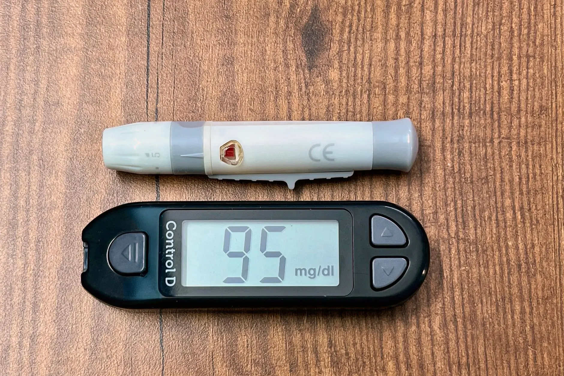 Close-up of a glucometer reading 95 mg/dl with a lancing device, ideal for diabetes and healthcare imagery