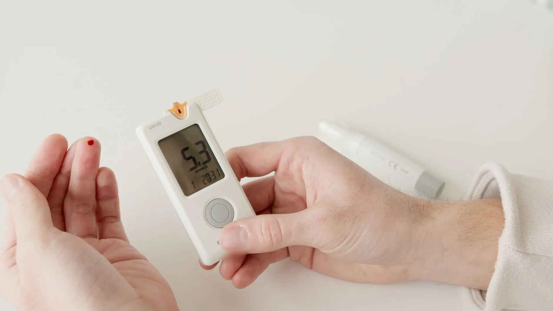 A close-up photo showing a glucometer and a hand pricking to measure blood sugar levels