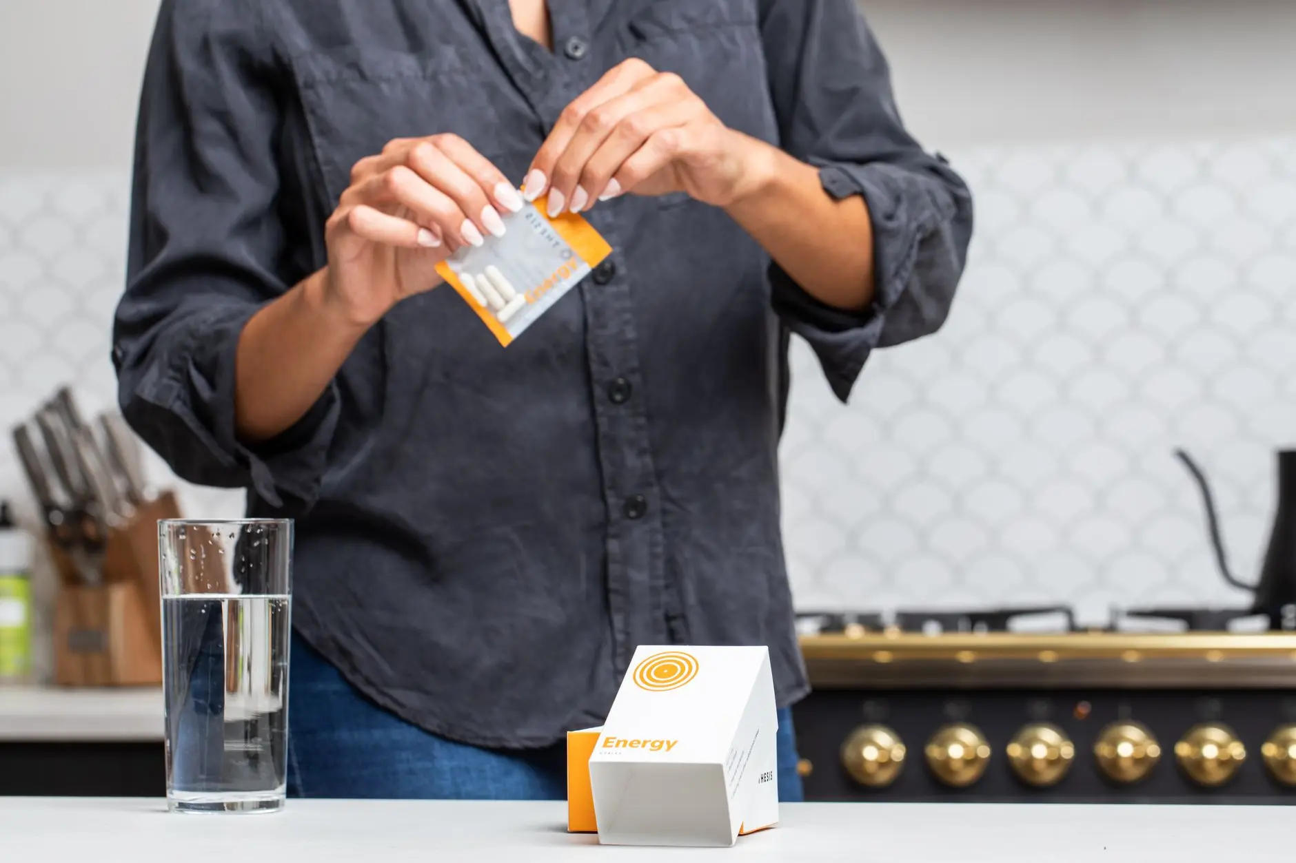 Close-up of a person opening an energy supplement packet in a kitchen setting